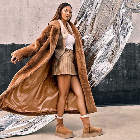 girl wearing zip up platform ugg boots and long brown faux fur coat